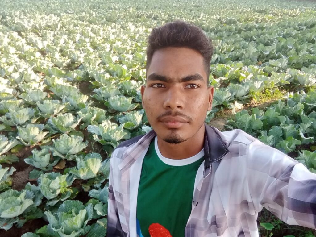 Young Bangladeshi farmer Asif Hasan taking a selfie in a large green cauliflower field in Kushtia