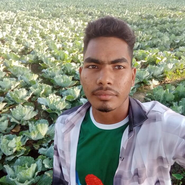 Young Bangladeshi farmer Asif Hasan taking a selfie in a large green cauliflower field in Kushtia